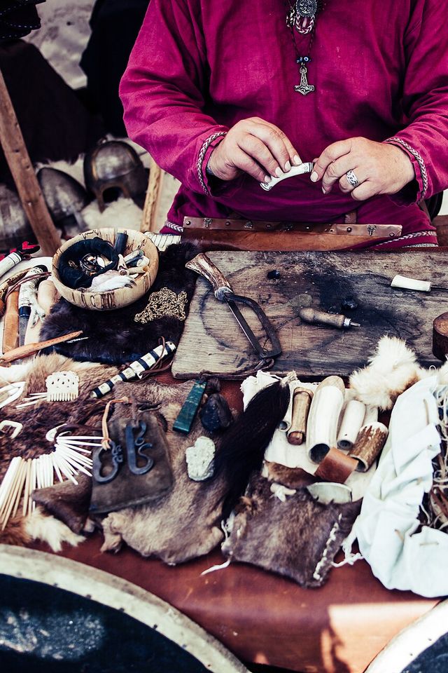 A leatherworker's bench crowded with hides, tools and small finished pieces